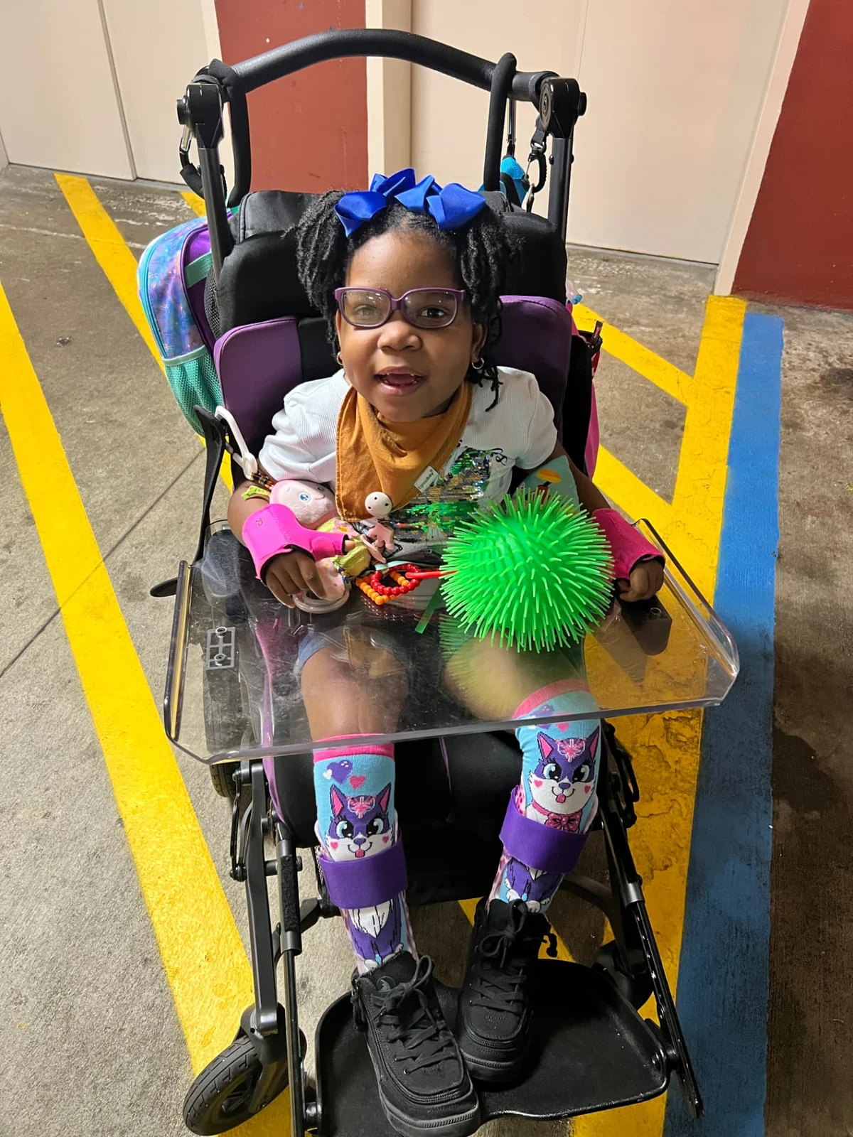 Phoenix smiling in her wheelchair with a bright blue bow