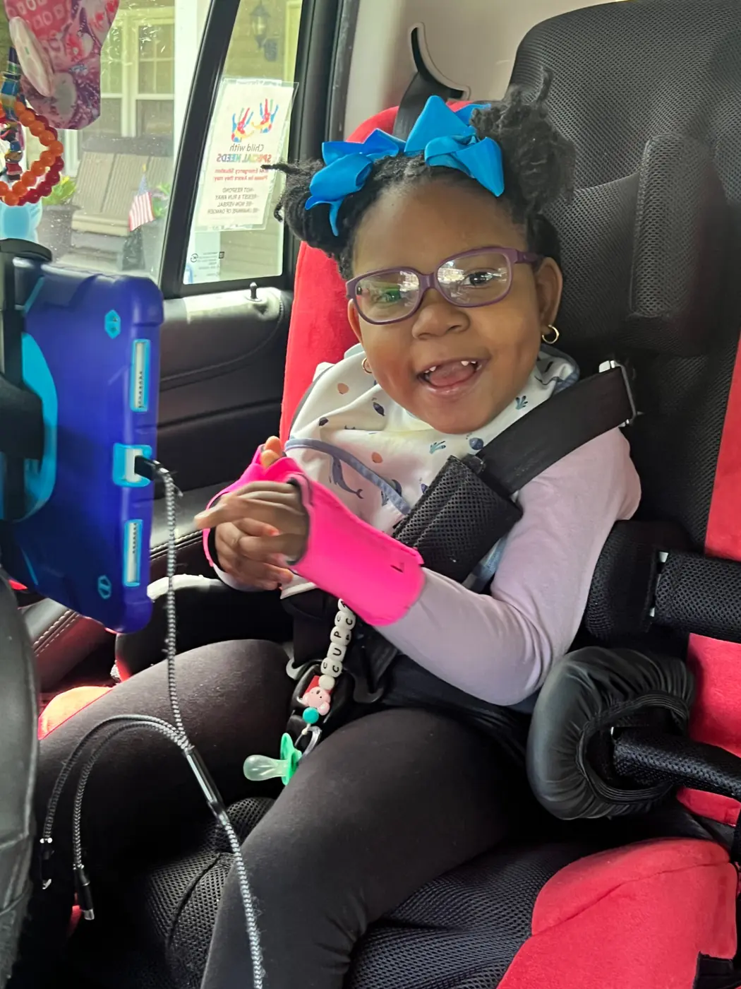 Cupcake smiling in her car seat with her tablet